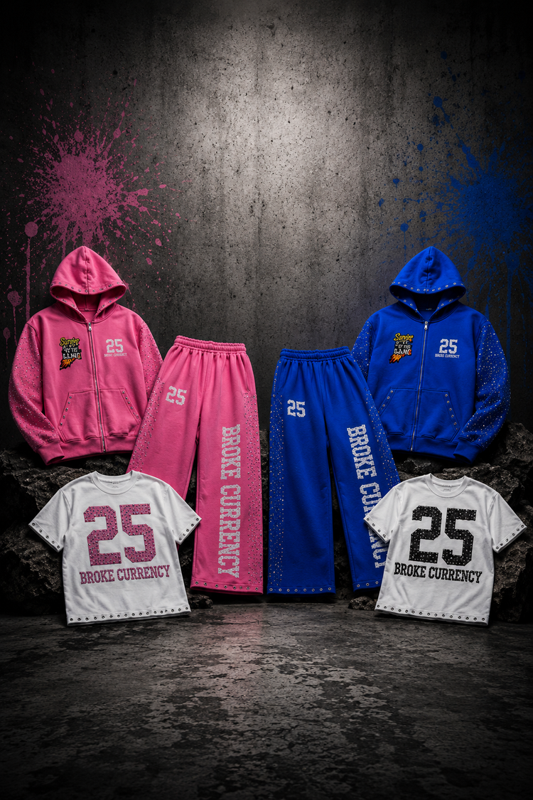 Four streetwear apparel pieces displayed against a dark textured wall: a pink zip hoodie and matching pink sweatpants, a blue zip hoodie and matching blue sweatpants, and two white T-shirts with large number 25 and BROKE CURRENCY text. The products are arranged symmetrically with paint splatters on the wall.