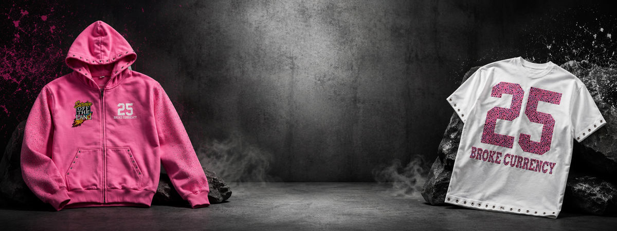 A pink zip-up hoodie and a white short-sleeve t-shirt, both featuring the number 25 and 'ROCK CURRENCY' in pink, displayed on a dark, smoky studio background.