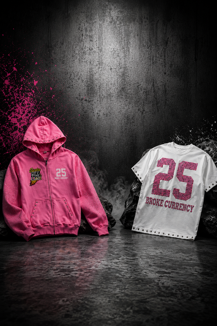 A pink zip-up hoodie and a white t-shirt both featuring the number 25 and 'BROKE CURRENCY' text, displayed against a dark, smoky studio background.