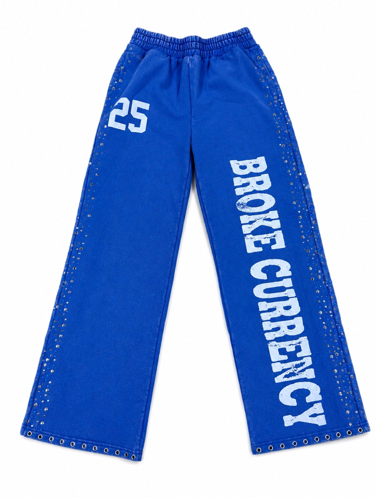 Blue wide-leg sweatpants with white text reading 'BROKE CURRENCY' down one leg, a white '25' on the other leg, and silver metal studs along the outer seams, shown on a plain white background.