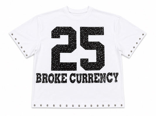 A white short-sleeve t-shirt with a black rhinestone-embellished '25' graphic and 'BROKE CURRENCY' text on the front, finished with silver-tone studs along the sleeve cuffs and hem.